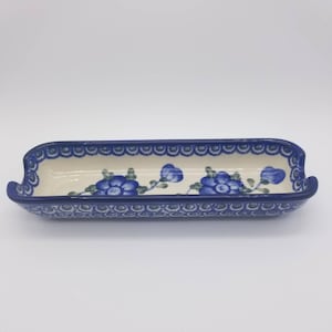 May include: A blue and white ceramic serving dish with a floral design. The dish has a scalloped edge and is perfect for serving bread, snacks, or appetizers.