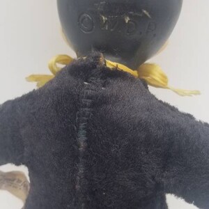 May include: Black and yellow vintage Mickey Mouse plush toy wearing a tuxedo. The toy has a sewn seam down the back and the words "O.W.D.P." are visible on the back of the head.