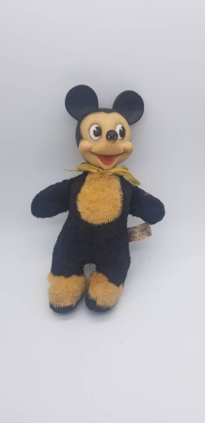 May include: Vintage black and yellow Mickey Mouse plush toy with a yellow bow tie. The toy has a sewn-on tag that reads "ANIMAL HOUSE".