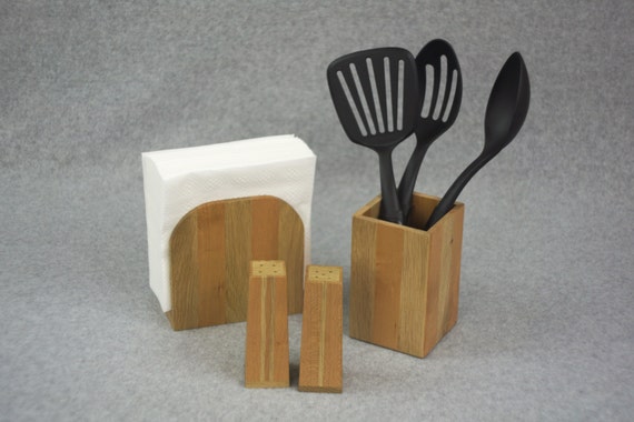 A matching three-piece kitchen counter set — napkin holder, utensil holder, and salt & pepper shakers — handcrafted from contrasting cherry and white oak for a warm, cohesive look that's hard to find anywhere else.