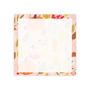 May include: A square notepad with a light pink border featuring a repeating pattern of orange pumpkins, red berries, brown acorns, and various autumn leaves in shades of yellow, green, and brown surrounding a large, blank white center area.