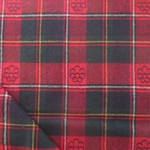 May include: A fabric featuring a red and black tartan plaid pattern with thin yellow and white intersecting lines. The design includes a repeating small fleur-de-lis style emblem integrated into the dark squares of the plaid grid.
