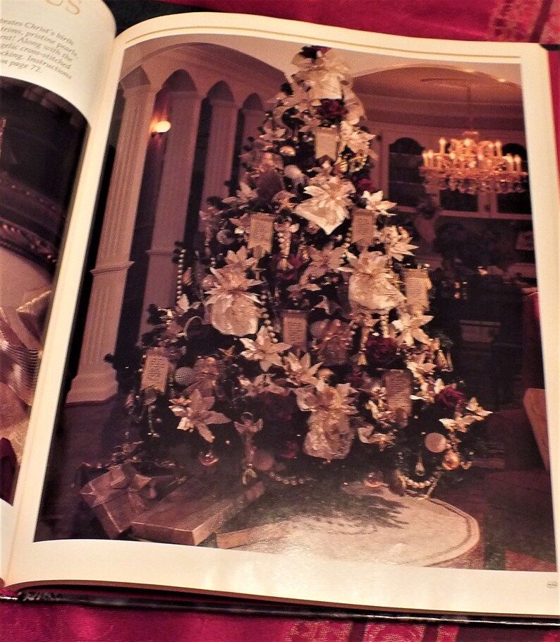 May include: A large, decorated Christmas tree with white and gold ornaments, red berries, and white poinsettias. The tree is in a large room with white columns and a chandelier.