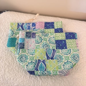 Könnte beinhalten: Zwei Stoffbeutel mit Kordelzug und Patchwork-Design mit blauen, grünen und weißen geometrischen Mustern.