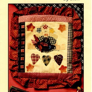 May include: A quilting pattern packet for a holiday angel pillow. The pattern features a red, white, and blue patchwork design with a heart-shaped angel and the text "Holiday Tyme Angel Pillow" and "#6264".
