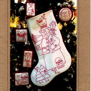 May include: A white felt stocking with red embroidery of a snowman holding a stick with a birdhouse on it. The stocking is decorated with small red embroidered ornaments of birds, birdhouses, and trees. The text "Bird Seed" is embroidered on the stocking. The text "Woodland Snowman RedWork - 125" is at the bottom of the image.