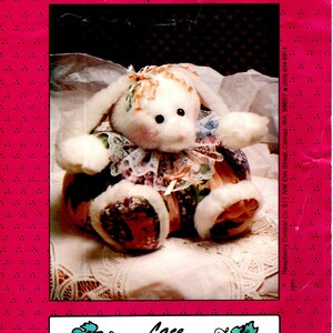 May include: A sewing pattern for a 12 inch bunny named "Lace" from Raspberry Cordial Co. The pattern features a white bunny with floral fabric and lace accents. The pattern is on a pink background with a white polka dot pattern.