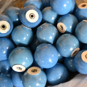 May include: A collection of light blue ceramic knobs with a glossy finish. Each knob is spherical with a metal insert for attachment. The knobs are in a clear plastic bag, suggesting they are for furniture or decorative use.