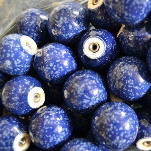 May include: A close-up of a collection of blue and white speckled ceramic knobs. The knobs are round and have a smooth, glossy finish.