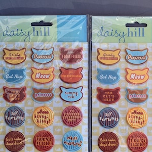 May include: Two packages of cat-themed decorative stickers. Each package contains 18 stickers with various cat-related phrases and images, including "Cat Nap", "Meow", "The Cat's Meow", "Princess", "Tummy Rub", "Furball", "Cats Rule, Dogs Drool", and "I Don't Fetch".