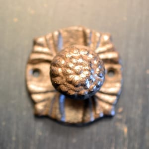 Peut inclure: Une poignée de porte en fonte avec un design décoratif. La poignée est de couleur brun foncé et a une surface texturée.