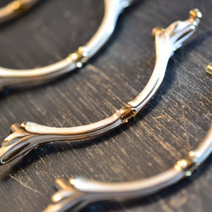 May include: Three ornate gold and white cabinet pulls with a decorative scroll design.