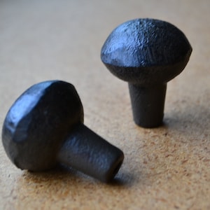 May include: Two black metal cabinet knobs with a rounded top and a short stem. The knobs have a slightly textured surface.
