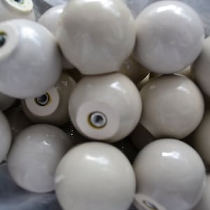 May include: A close-up of a group of white ceramic knobs. The knobs are round and have a smooth, glossy finish.