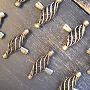 May include: A set of eight antique gold-toned cabinet knobs with a twisted wire design. The knobs have a decorative, ornate look.
