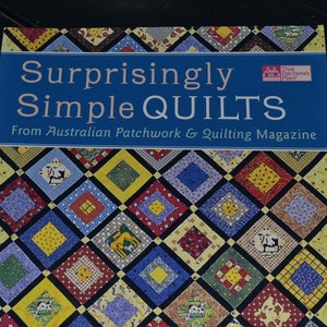 May include: A book titled "Surprisingly Simple Quilts" from Australian Patchwork & Quilting Magazine. The cover features a quilt design with colorful squares and various animal and object illustrations. The book has a blue banner with white text.