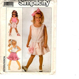 May include: Simplicity pattern 9180 for girls' clothing. The pattern features designs for a top and skirt set with bow accents. The image shows illustrations of the finished outfits, including a pink and white striped ensemble and a polka dot top with a pink skirt.