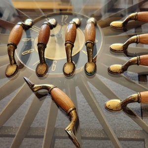 May include: A set of eight wooden and brass cabinet knobs with a simple design. The knobs have a light brown wood finish and a brass base.