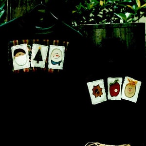 May include: Two black sweatshirts with appliqued designs. One features a Santa, Christmas tree, and snowman. The other has a flower, apple, and smiling face. The image is framed with the text "Stitches and Sawdust" and "Warm Wearables".