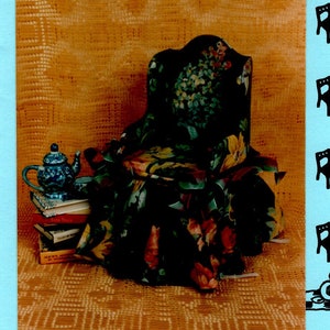 May include: A pattern for a fabric chair, called "Fancy Fold Flat Chair", by Barbara Willis Designs. The chair is shown in a green and brown floral fabric. The pattern is shown on a blue background with a black and white checkered border.