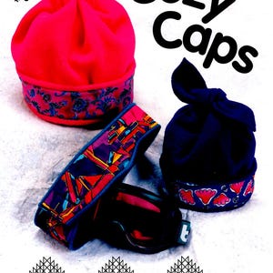 May include: Three cozy fleece hats with colorful patterned trim. The hats are on a white background. The text "Cozy Caps" is in large black letters at the top of the image. The text "Timber, Lane, Press" is at the bottom of the image with contact information.