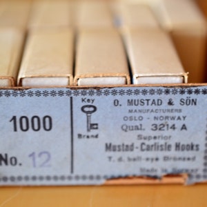 May include: A box of 1000 Mustad & S&ouml;n Superior Mustad-Carlisle Hooks, size 12, manufactured in Oslo, Norway. The box is brown with a blue label and a small illustration of a key.