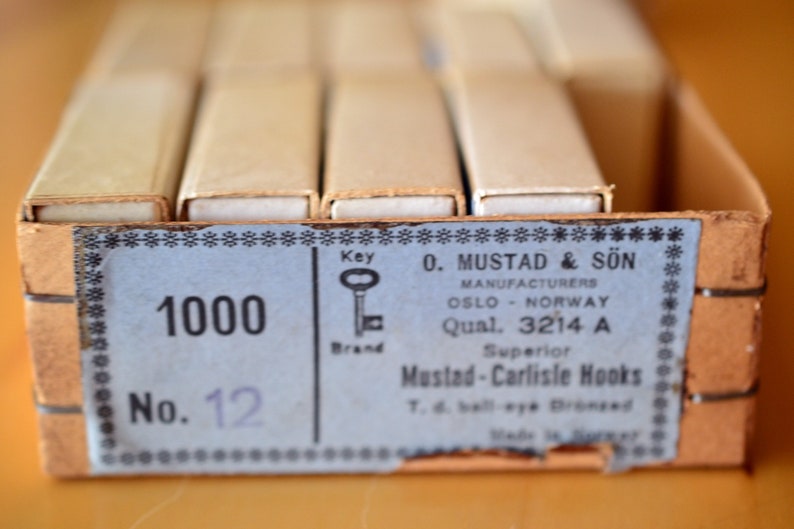May include: A box of 1000 Mustad & S&ouml;n Superior Mustad-Carlisle Hooks, size 12, manufactured in Oslo, Norway. The box is brown with a blue label and a small illustration of a key.