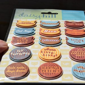May include: A sheet of 16 colorful cat-themed stickers with various sayings, including "Frisky feline", "Purrrri", "Furry Friend", "Cat Nap", "Meow", "Got attitude?", "The cat's meow", "Princess", "Tummy rub", "I'm purrrrriect", "Lil' furball", "Here kitty kitty", "Cats rule, dogs drool!", "I don't fetch!", and "Your highness".