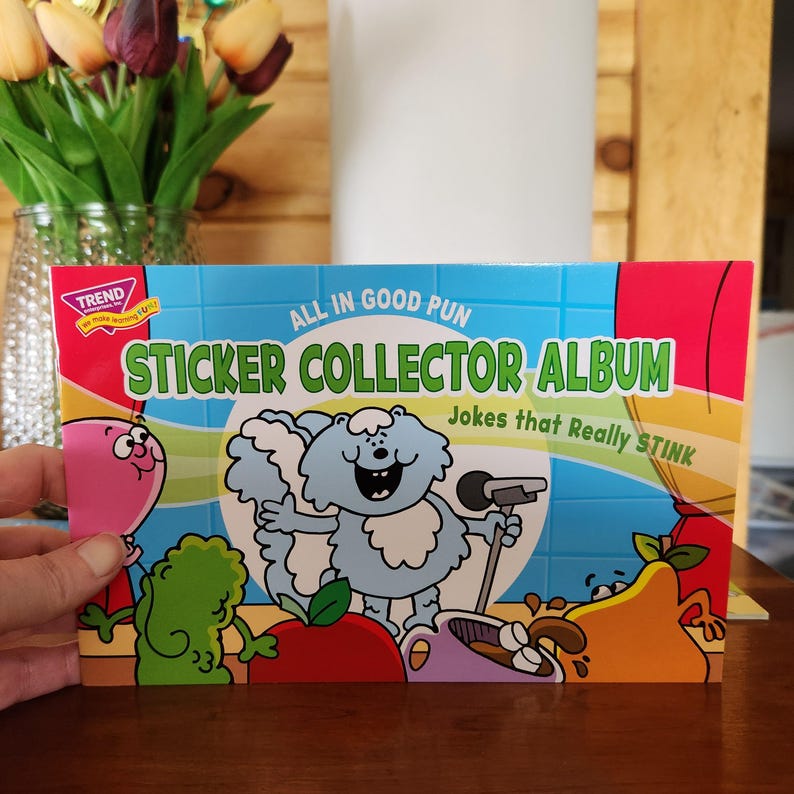 May include: A colorful sticker collector album with the text "ALL IN GOOD PUN" and "STICKER COLLECTOR ALBUM Jokes that Really STINK." The cover features cartoon characters and a light blue background.