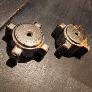 May include: Two round, chrome-plated, metal knobs with black plastic bases. One knob is labeled "HOT" and the other is labeled "COLD".