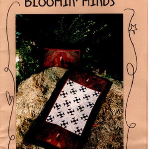 May include: A red and black quilt with a star pattern on a hay bale. The quilt is made with a white background and black stars. The quilt is sitting on a hay bale with a red and black pillow behind it. The pillow has a turkey design on it. The image is titled "Bloom'n Minds".