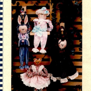May include: Four handmade fabric dolls with different animal designs. A bunny doll in blue overalls, a bear doll in a pink and white dress, a cat doll in a black dress, and a sheep doll in a pink and blue dress.