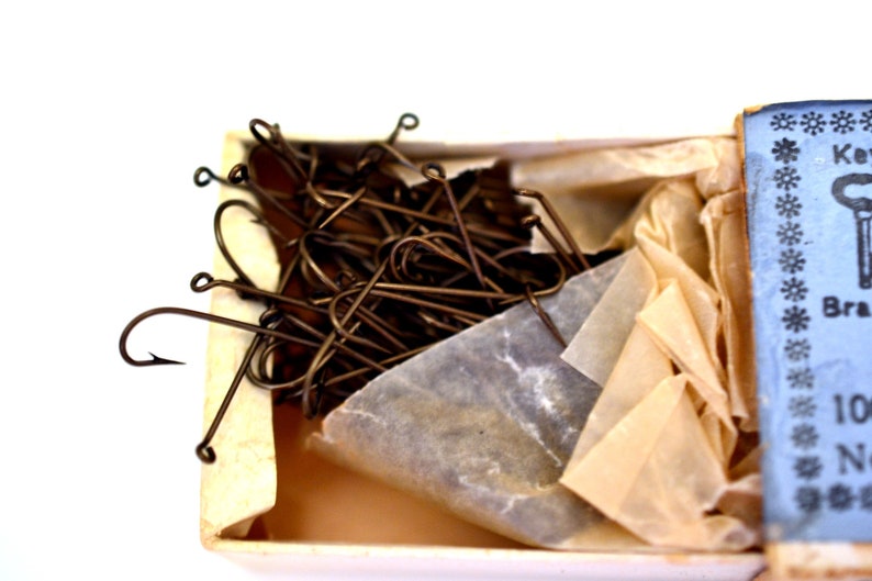 May include: A box of 100 brass fishing hooks, wrapped in tissue paper. The box is blue with white snowflakes and the text "Key Brand" and "100 No. 6".