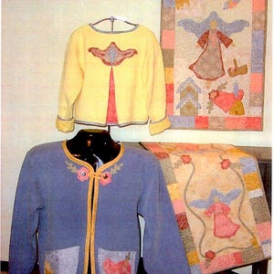 May include: Two blue and yellow knitted cardigans with appliquéd designs. The cardigans are displayed on mannequins. Two quilted wall hangings with angel designs are displayed behind the mannequins.