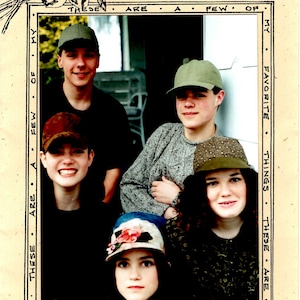 May include: A group of four friends pose for a photo. They are all wearing hats and smiling. The photo is framed with a decorative border and the text "Favorite Things" and "Just Friends" is printed on the image.