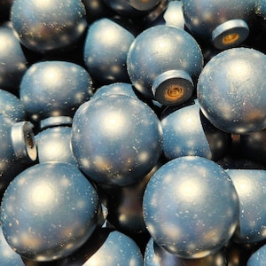 May include: Close-up of a collection of blue, spherical cabinet knobs. The knobs have a metallic sheen and are speckled with white. Each knob has a small, cylindrical base with a visible screw hole. The knobs are likely for furniture or decorative use.