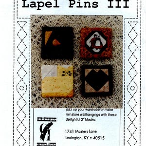 May include: A product package titled "Foundation Impressions Lapel Pins III" featuring four square fabric pins. The pins are approximately 2 inches square and feature various designs, including a geometric shape and a figure. The package includes the address 1741 Masters Lane, Lexington, KY 40515.