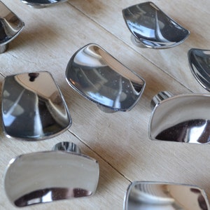 May include: A set of 10 chrome cabinet knobs with a curved, rounded design. The knobs are shiny and reflective.