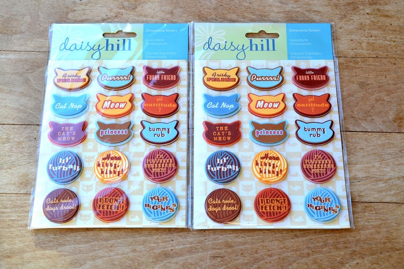 May include: Two packages of colorful cat-themed stickers with phrases like "Purrrr!" and "The Cat's Meow".
