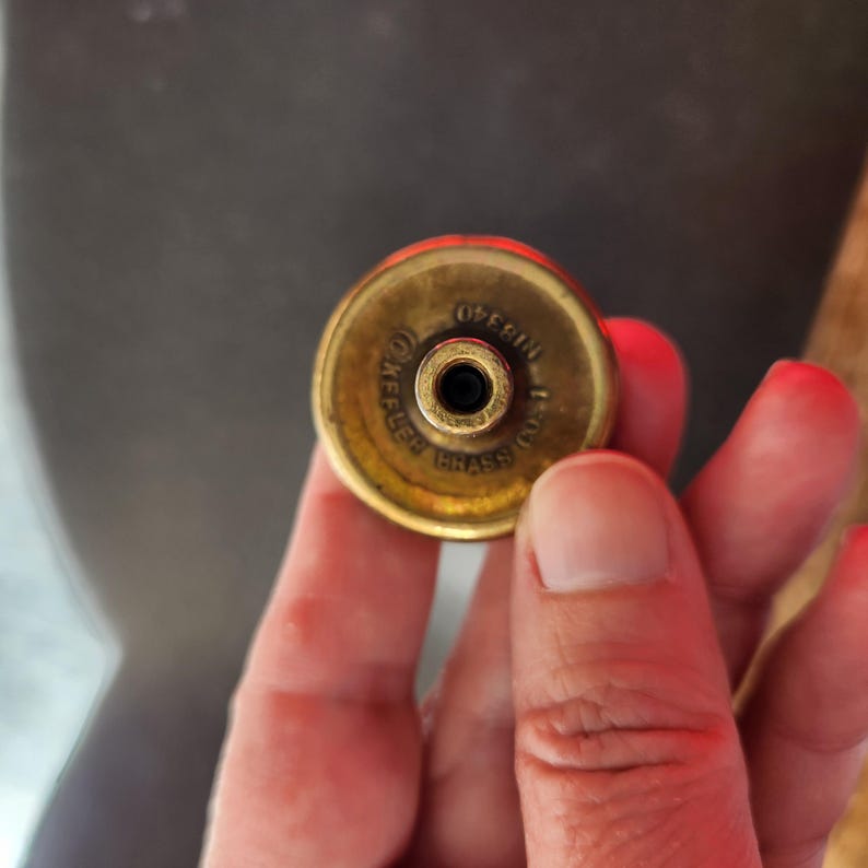 May include: Close-up of a brass, round,  metal object with the text "KEELER BRASS CO. 1" and "OBERLIN" engraved on the top.