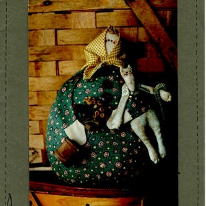 May include: A green and white patterned fabric doll with a yellow and white checkered bonnet and a white fabric cat sitting on her lap. The doll is 8 inches tall and is labeled "#118 Sophie".