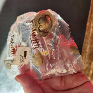 May include: A gold-colored cabinet knob with a decorative clover design, packaged with two screws. The package is labeled "Telwith International Ltd."