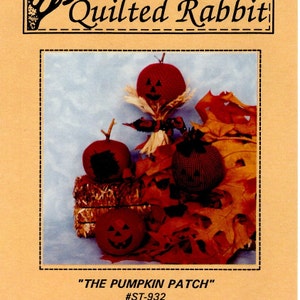 May include: A craft pattern for making a pumpkin patch with four pumpkins. The pumpkins are made of fabric and have painted jack-o-lantern faces. The pattern is titled "THE PUMPKIN PATCH" and has the number #ST-932.