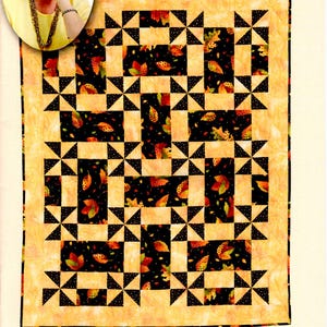 May include: A quilt with a patchwork design featuring black, white, and orange squares and triangles. The squares have a pattern of leaves on a black background.