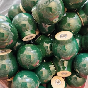Peut inclure: Une collection de boutons en bois vert avec un centre brun clair. Les boutons sont ronds et ont une finition lisse et brillante.