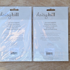 May include: Two packages of Daisy Hill Dimensional Stickers. The white packages have a black and white design with the text "Use these delightful Dimensional Stickers to embellish scrapbooks, greeting cards, boxes and much more!"