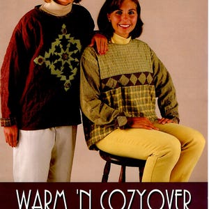 Peut inclure: Deux femmes portant des pulls faits à la main. L'un est marron foncé avec un motif géométrique vert et beige, l'autre est à carreaux verts et marron avec un motif de losanges. Le texte "WARM 'N COZYOVER" est en bas.