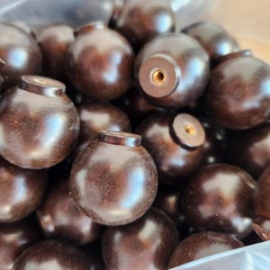 May include: A collection of dark brown wooden knobs with a rounded shape and a small, cylindrical top. The knobs have a smooth, polished finish and a threaded insert for easy installation. These knobs are suitable for cabinets and drawers.