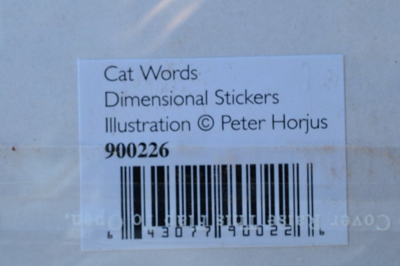 May include: White label with black text that reads "Cat Words Dimensional Stickers Illustration &copy; Peter Horjus" and the number "900226". A black and white barcode is below the text.