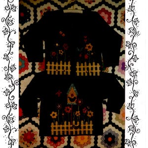 May include: A black sweatshirt with a flower patch design. The design features a birdhouse, flowers, and a picket fence. The text "Flower Patch Sweatshirt" is printed below the design.